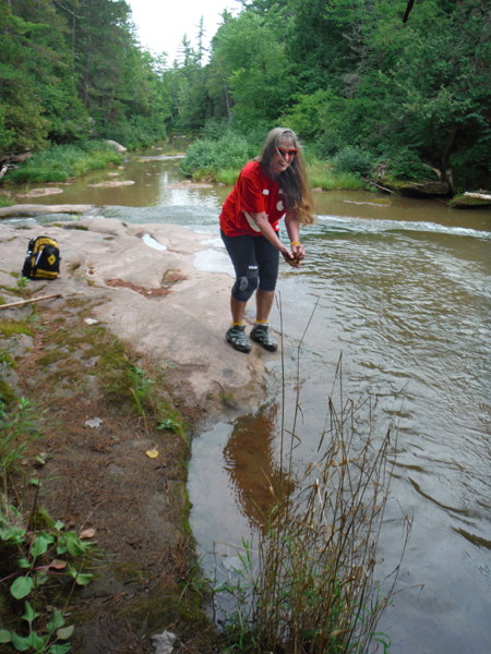 Karen wets her hiking rag in the river